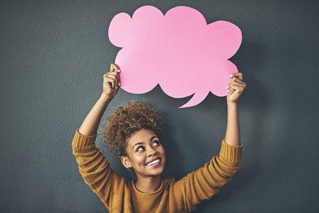 woman smiling holding speech bubble above her head.
