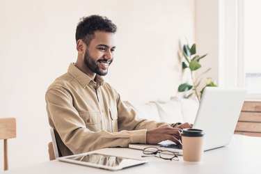  Man smiling while working on laptop. 