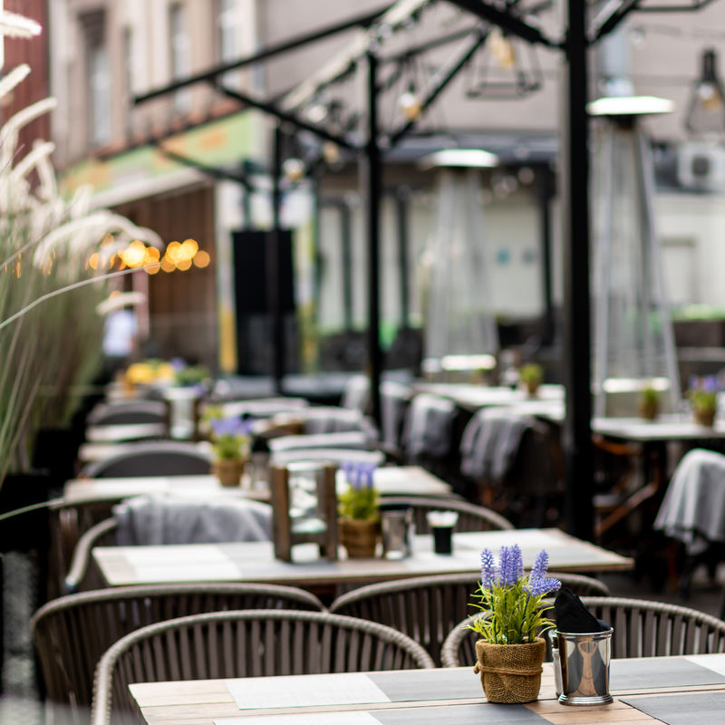 Outdoor restaurant with tables set up waiting for customers to arrive.