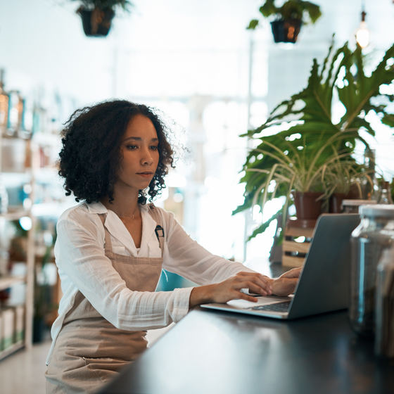 Woman business owner inside her business working on laptop.
