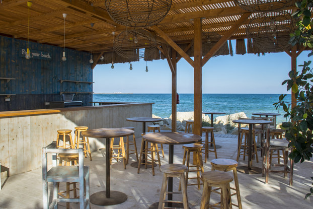 Outdoor beachfront bar with stools, empty and ready for patrons to arrive.