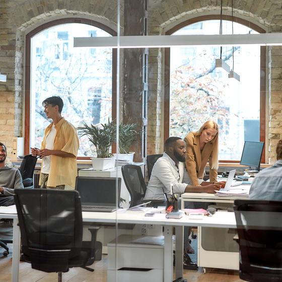 Team of employees sitting at desks inside a bright office.