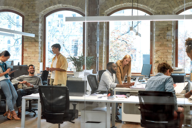 Team of employees sitting at desks inside a bright office.