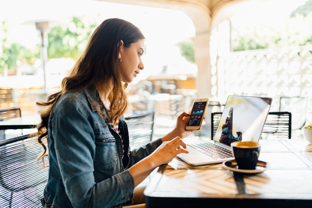 Woman sitting in a cafe on laptop and phone.