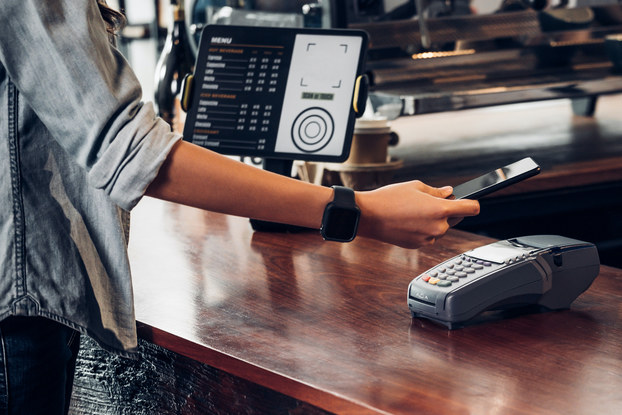 Woman paying at cafe with contactless mobile payment.