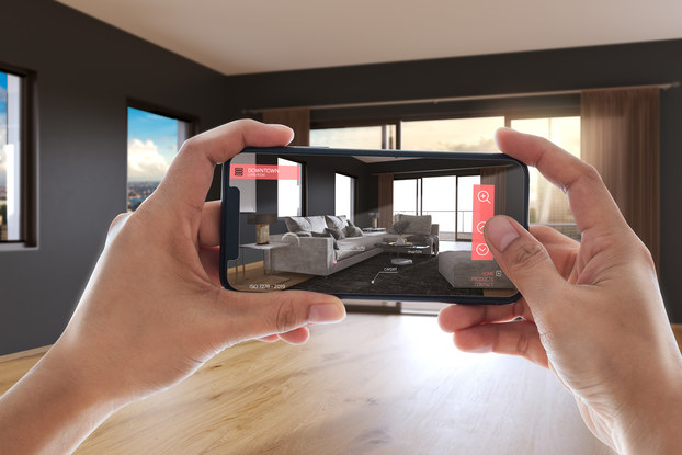 Person using an augmented reality app on their phone to picture furniture in their space before buying.