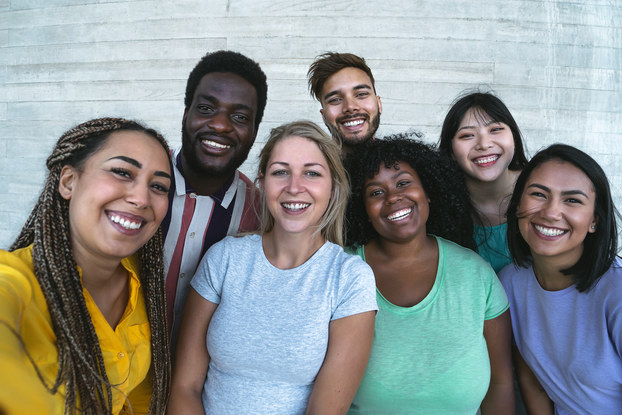 A diverse group of people stands shoulder-to-shoulder, smiling.