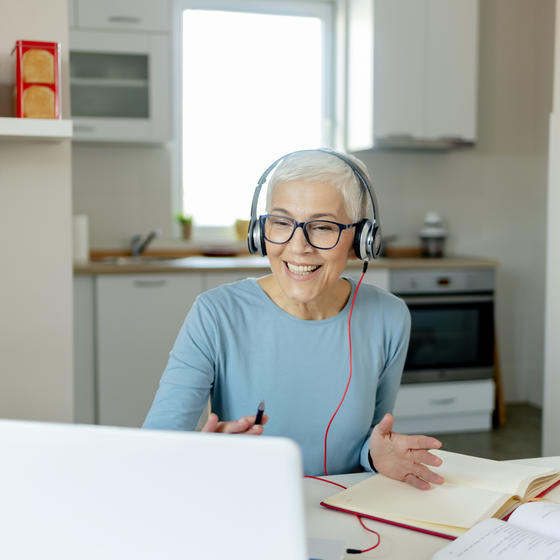 Woman working on headset and laptop in her dining room.