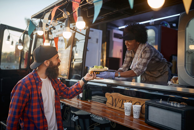 Customer purchasing food from the owner of a food truck.