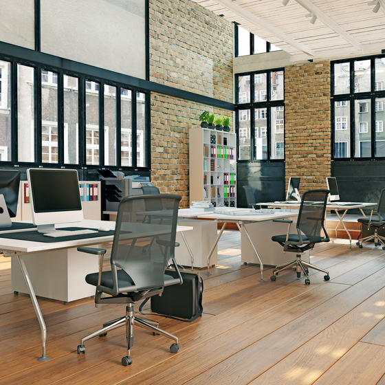 Modern office setting with desks and large windows.