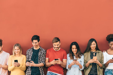  Group of young people having fun using smartphones outdoors 