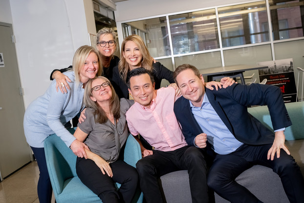 Men and women smile in a workplace lounge
