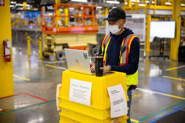 Amazon associate working inside the warehouse wearing PPE.