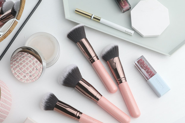 Luxie's beauty products and brushes displayed on a white surface.
