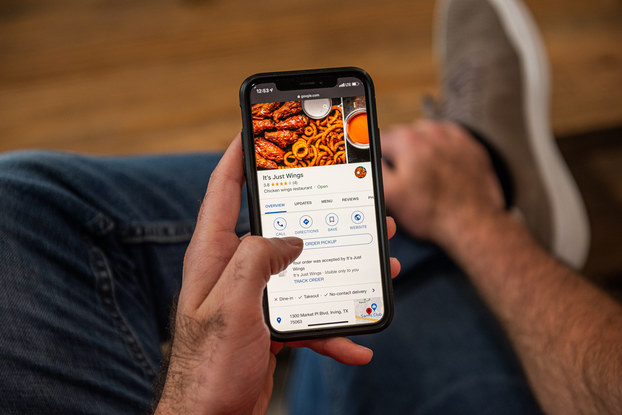 Person holding phone ordering It's Just Wings through a food delivery app.