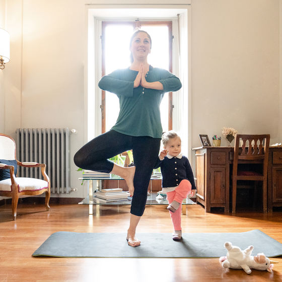 Woman doing yoga with her daughter.