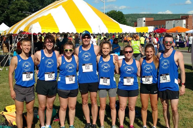 Running race participants pose outdoors with race bibs