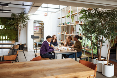  Team of employees at a table inside a trendy, modern office space. 