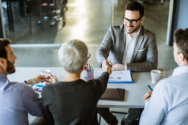  Happy businessman shaking hands with member of human resource team in the office. 