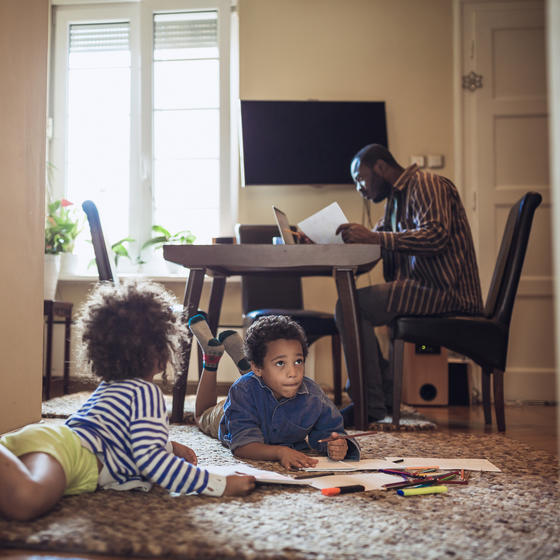 Father working from home while kids play on the floor.