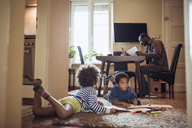  Father working from home while kids play on the floor. 