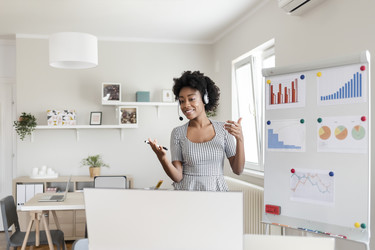  Woman presenting virtually at home in front of a board with charts and graphs. 
