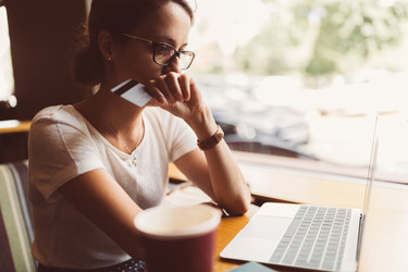  A concerned woman looks at her laptop with a credit card in hand. 