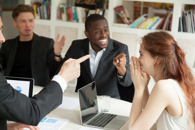Employees happily celebrate colleague's achievement who appears shy.