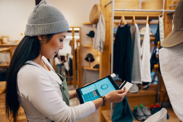Retail shop clerk taking a mobile credit card payment on a digital tablet.