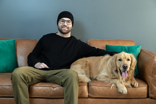 Man sits with a happy dog on a leather couch