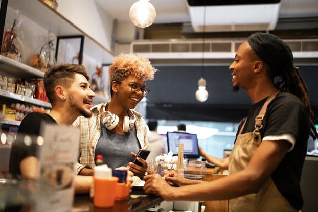 Happy customers making a purchase at a cafe.
