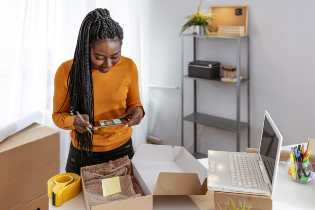 Young business owner packing cardboard box to deliver to a customer.
