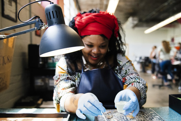 An employee of Rebel Nell works on a piece of jewelry made from fallen graffiti paint.