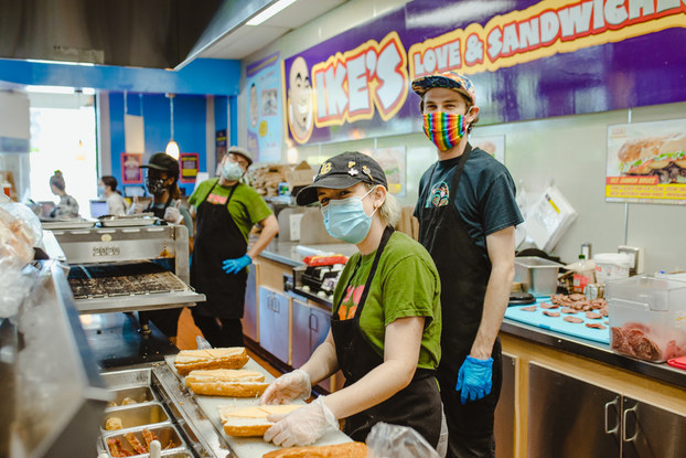 Employees working inside a location of Ike’s Love & Sandwiches.