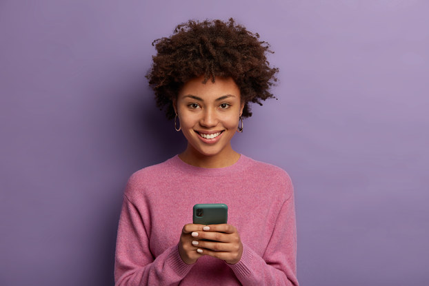 How to Run A Successful Digital Marketing Campaign Woman standing on phone in front of a purple background.