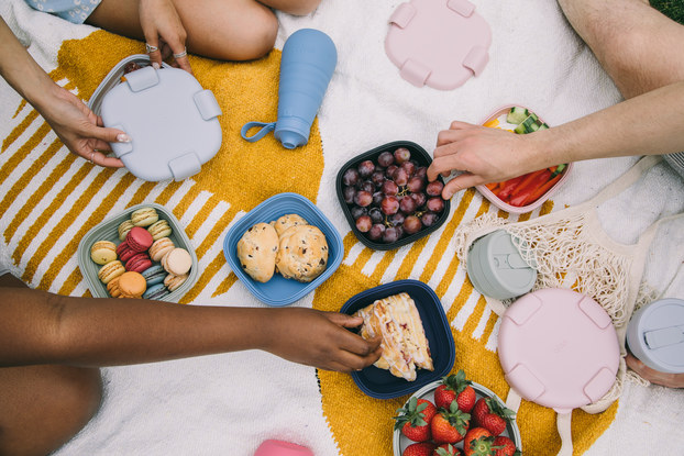 Top view of people having a picnic with food in Stojo collapsible containers.