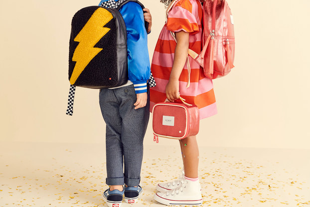 Two children wearing backpacks and holding a lunchbox from STATE Bags.