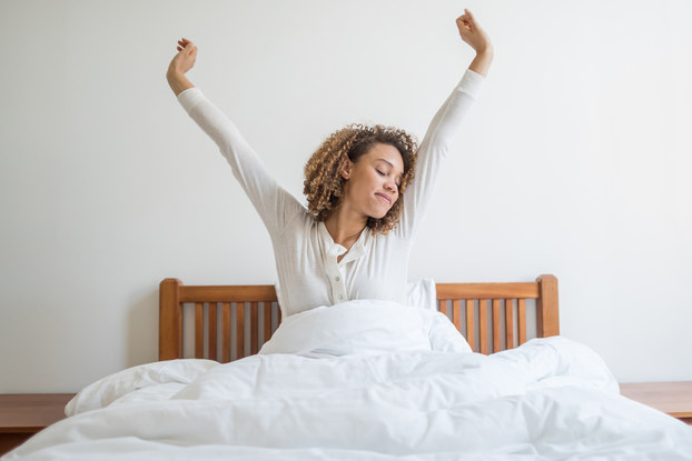 Woman stretching while waking up in bed.