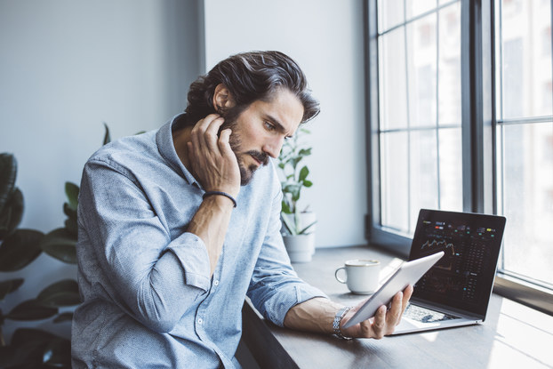 Businessman working using multiple devices at an office near a window.