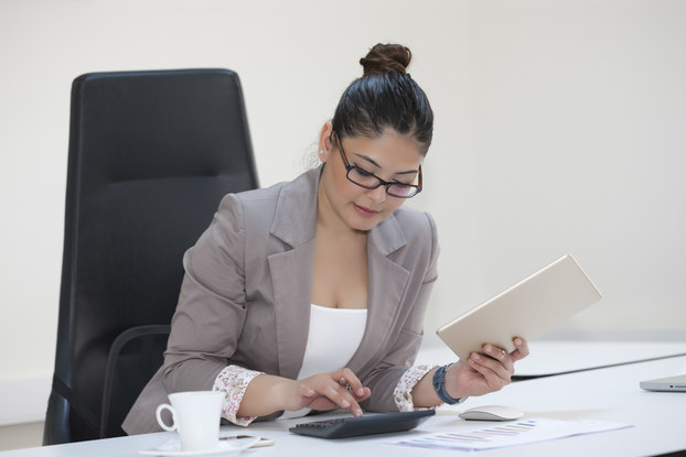 Businesswoman calculating finances at office desk.