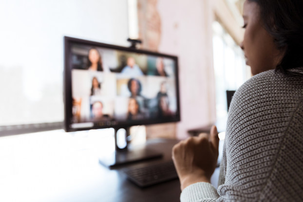 Woman working remotely tuned into a video conference with colleagues.