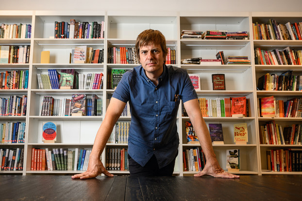 Andy Hunter, CEO, Bookshop.org, in front of bookshelves of books.