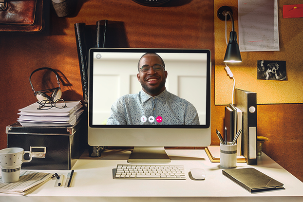 A Talkspace therapist on the screen of a computer monitor that is sitting on the desk of a person's home office.