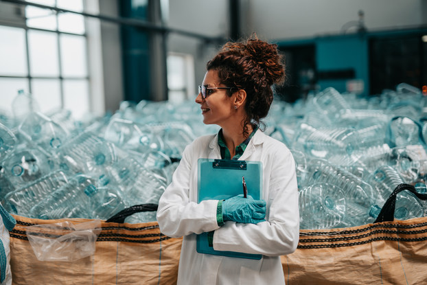 Young happy female worker in bottling factory recycling department.