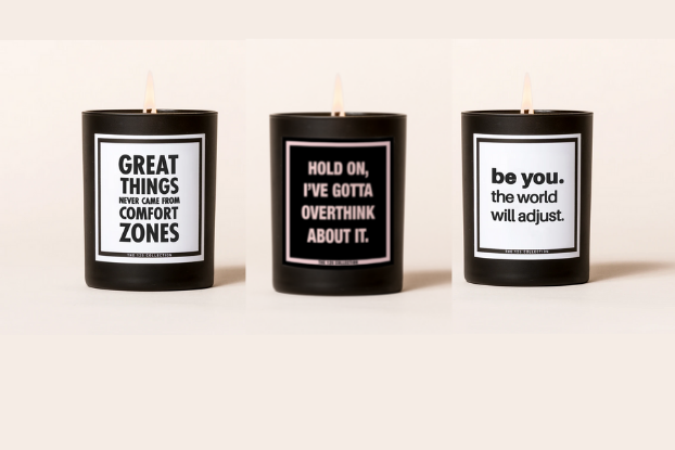 A product image of three candles in black tins, each with a motivational message written in contrasting colors.
