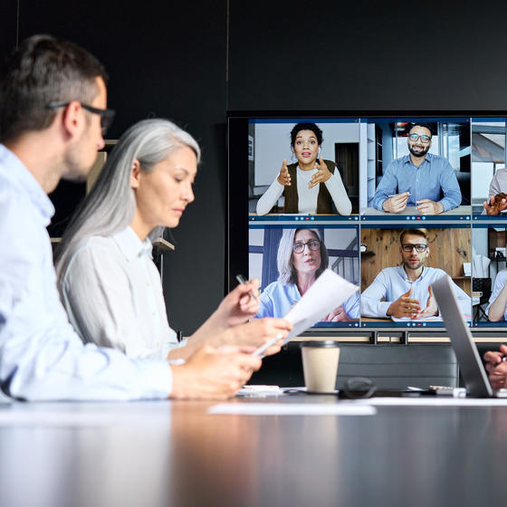 Meeting with some employees on videoconference and others in modern meeting room.