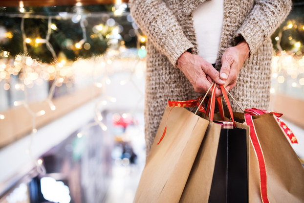 Person's hand holding holiday-themed shopping bags.