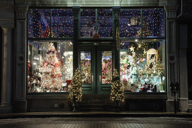Exterior of a shop where you can see holiday lights and decor set up inside.