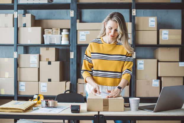 Woman boxing and stacking packages for shipment.