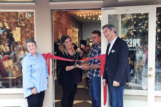 Business owners open their storefront at a ribbon-cutting ceremony